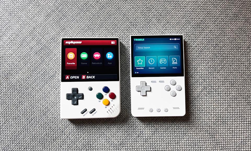 Two Game Boy-style gaming handhelds, the Miyoo Mini Plus and TrimUI Brick, sit on a gray couch cushion.